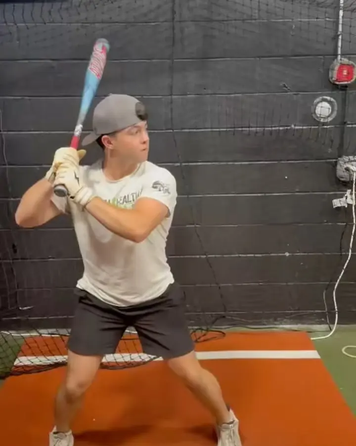 Athlete in a grey cap set up in the batter's box at the indoor facility